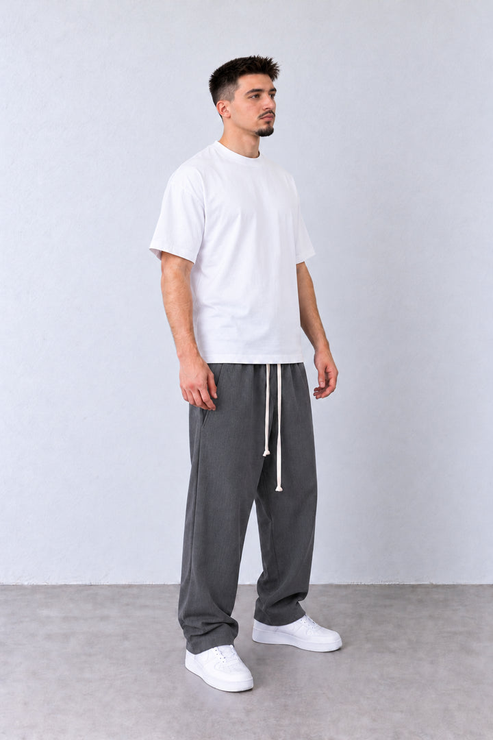 Szürke férfi baggy nadrág elülső varrásokkal. Modellen, laza pózban.