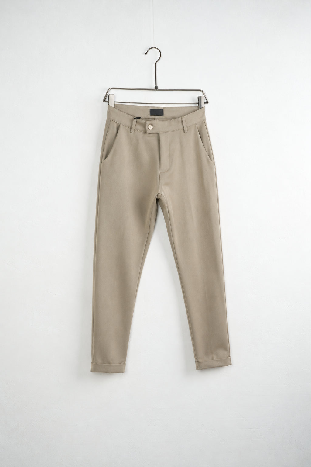 Bézs férfi slim fit nadrág. Termékfotó vállfán, ferde nézetből.