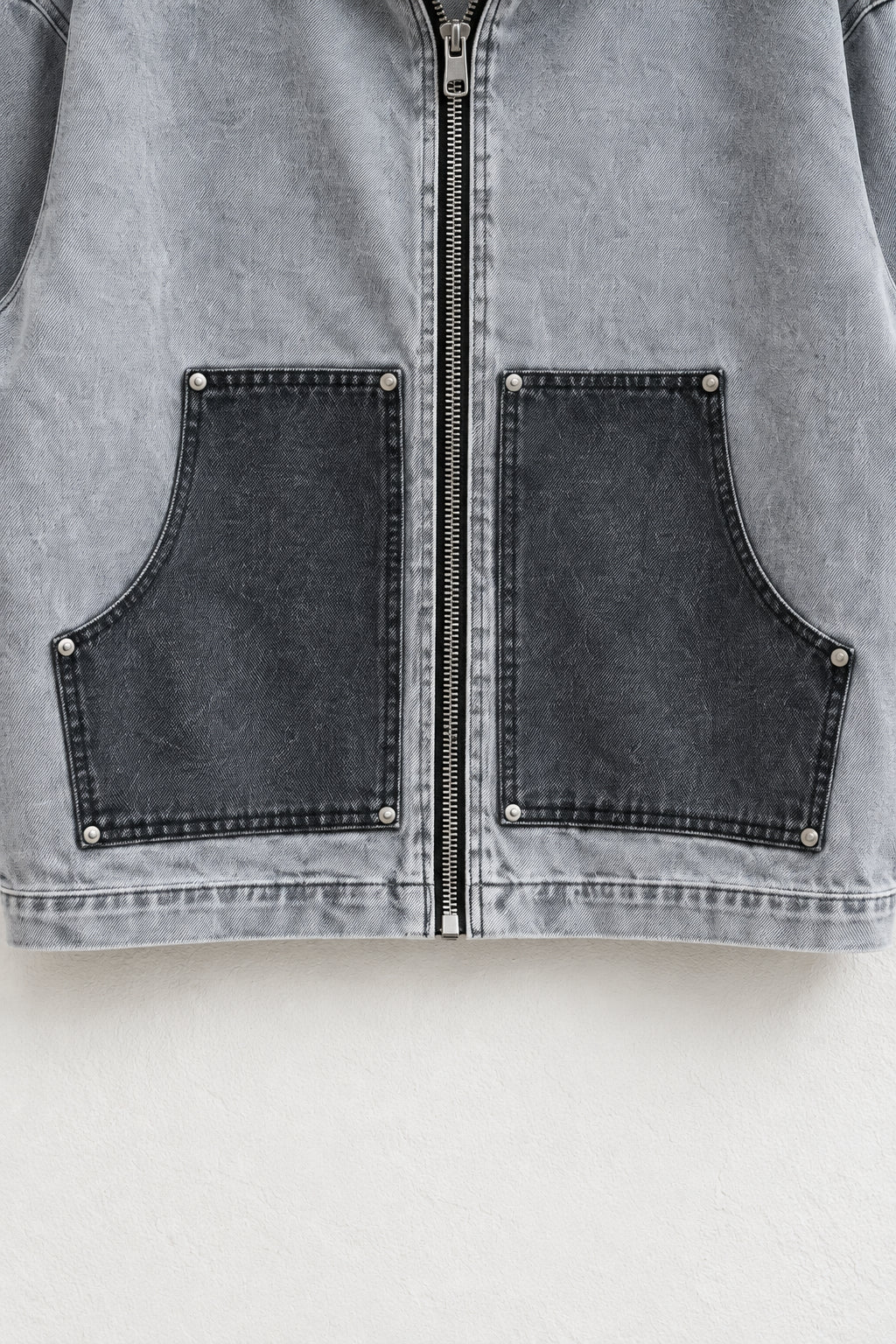 Detaliu al buzunarelor antracit, niturilor și fermoarului jachetei din denim gri
