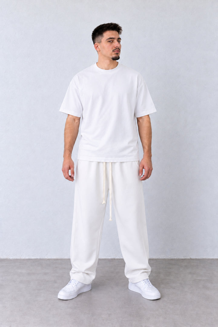 Pantaloni Baggy Felpați Bărbați Albi, vedere pe model cu poziție alternativă a brațelor și picioarelor.