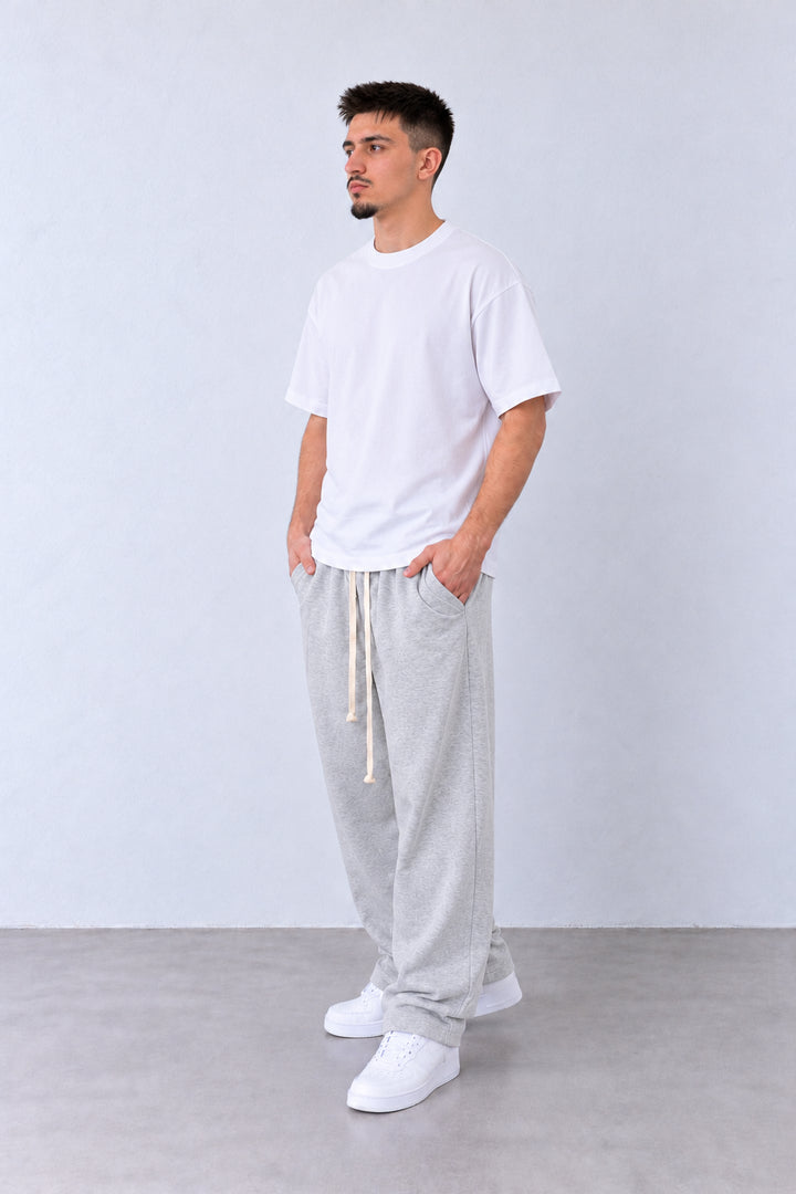 Pantaloni Baggy Felpați Bărbați Gri Melanj, vedere integrală pe model cu capul ușor întors sau înclinat.