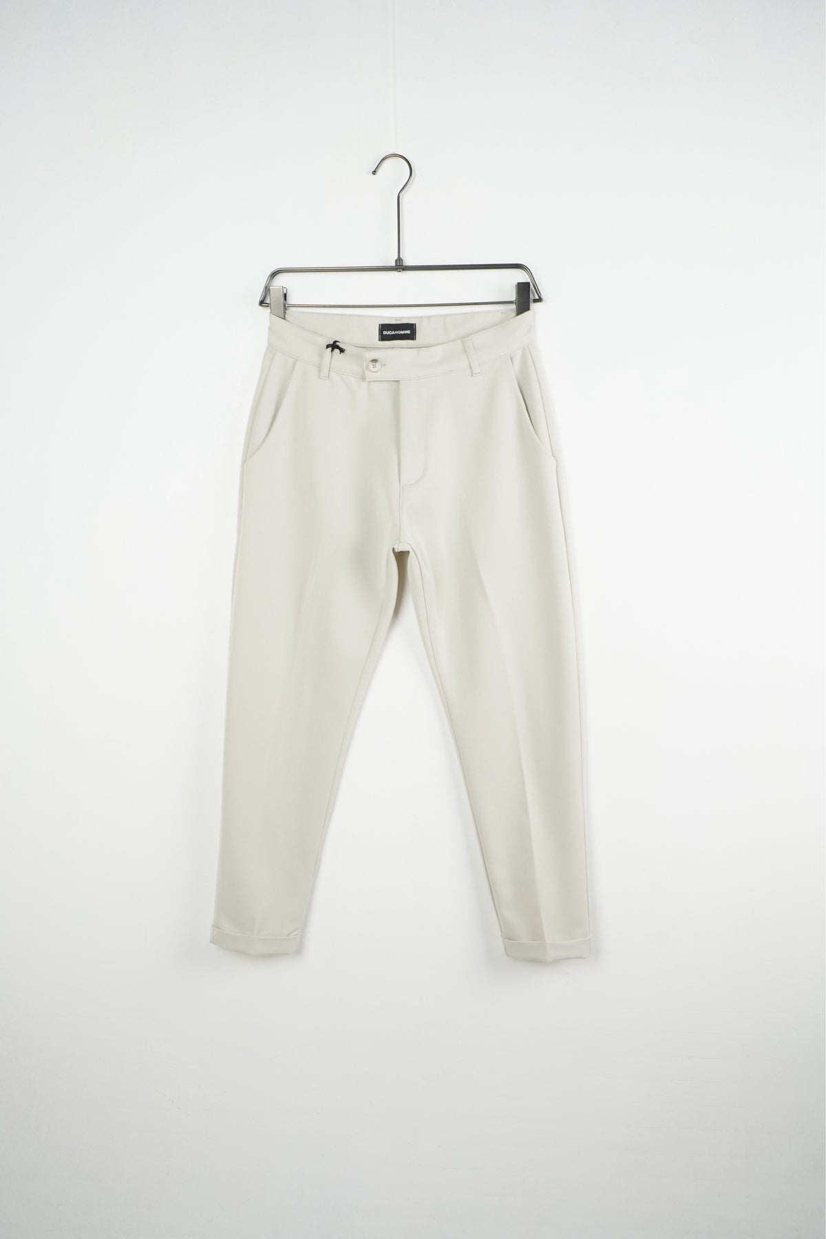 Krémszínű férfi slim fit nadrág. Termékfotó vállfán, elölnézetből.