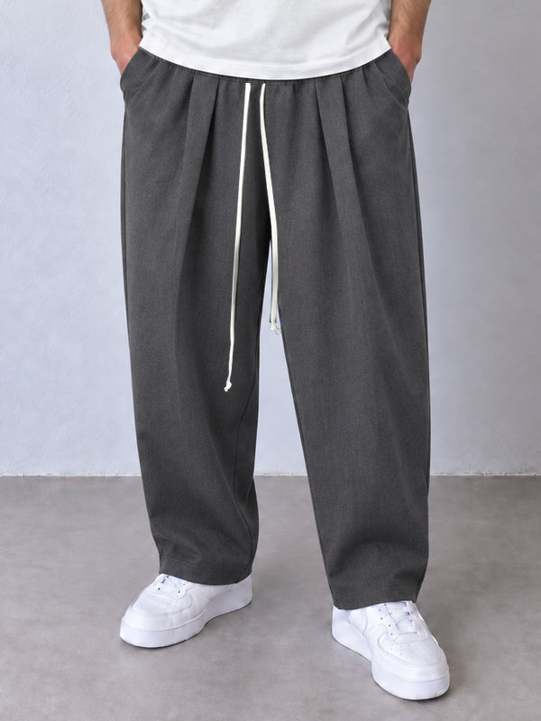 Pantaloni gri, cadru frontal apropiat cu pense, șnur lung și tivuri simple.