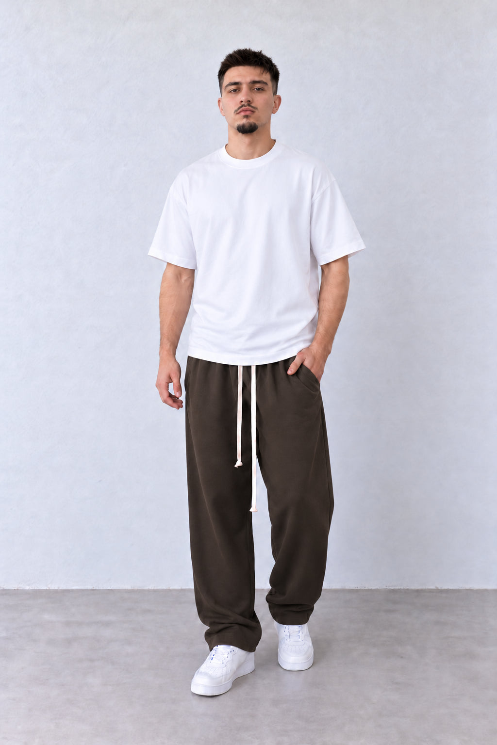 Barna férfi baggy nadrág elülső varrásokkal. Modellen, laza pózban.