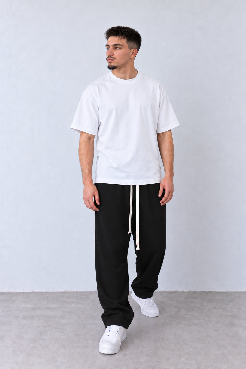 Pantaloni negri cu talie elastică, croială baggy și tiv drept, pe model în postură relaxată.