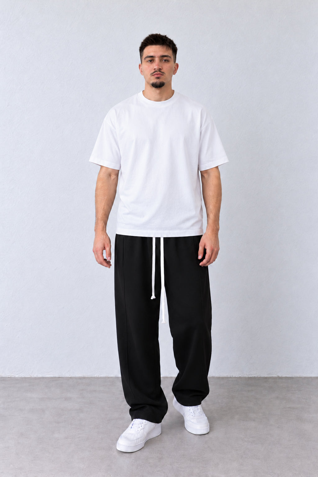 Pantaloni baggy negri pentru bărbați, cu șnur lung și cusătură laterală lângă buzunar, ținută integrală pe model.