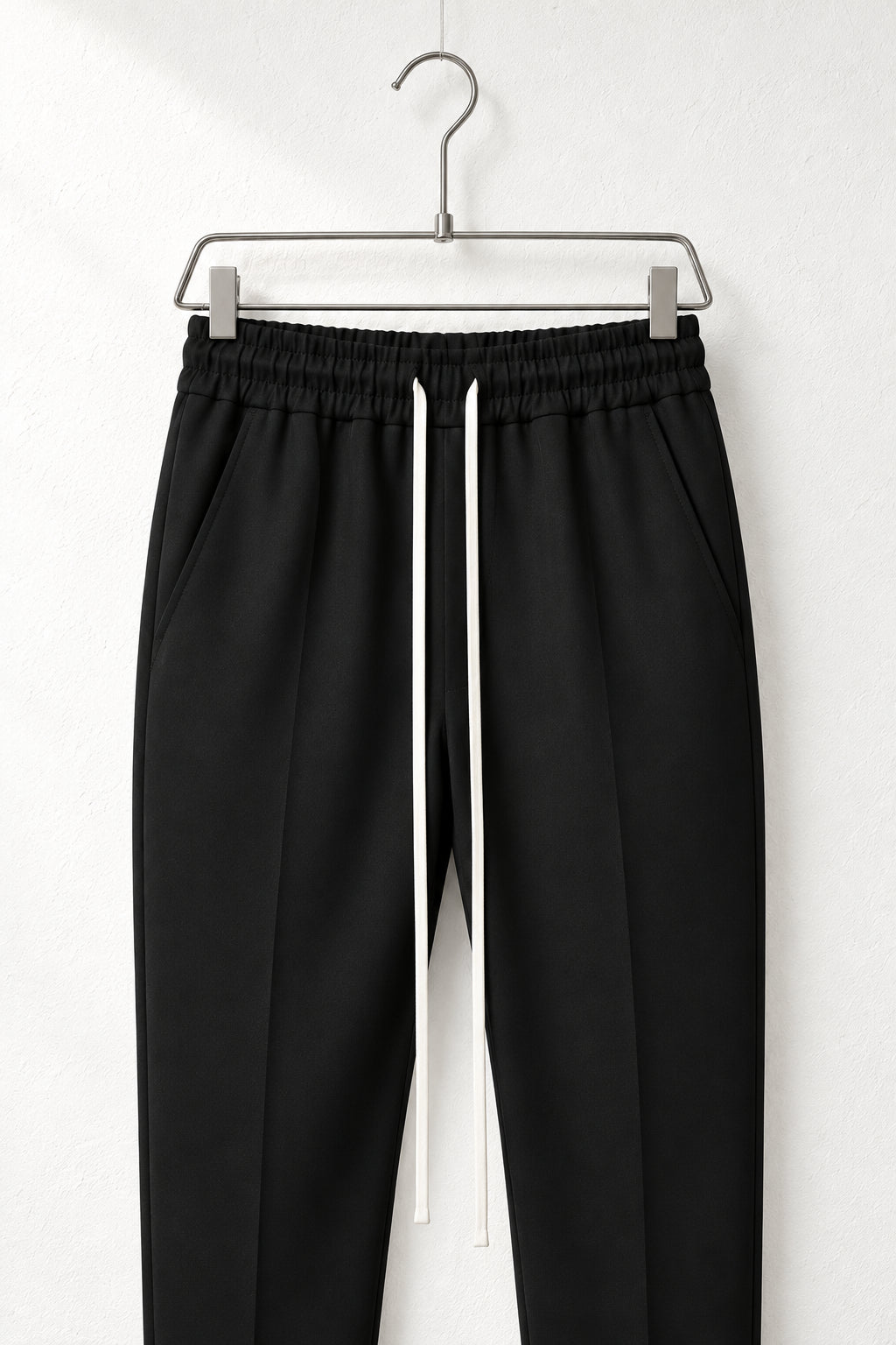 Detaliu talie elastică, buzunare și șnur lung la pantalonii negri