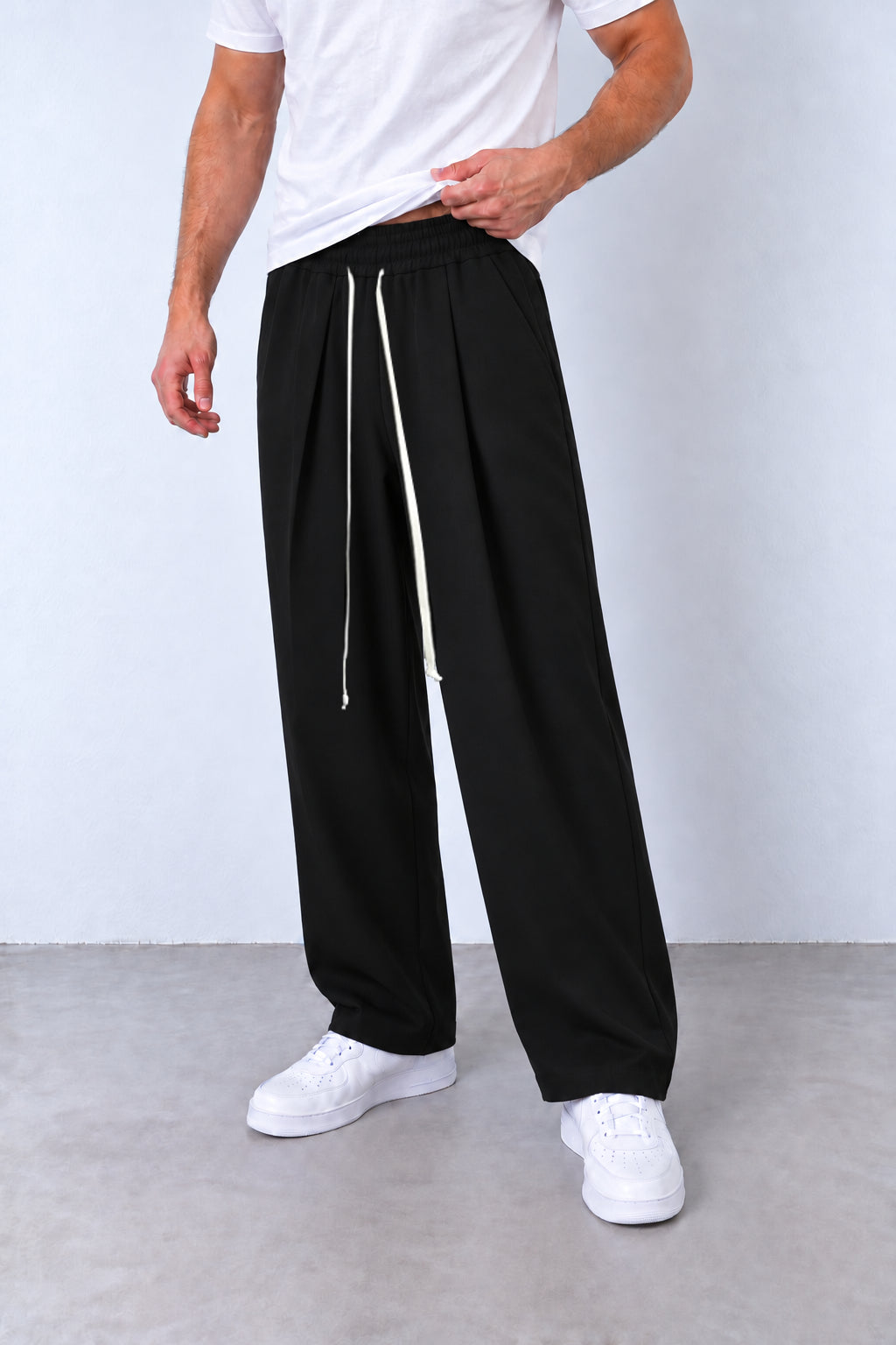 Pantaloni negri cu pense DU-019106 pe model, vedere din trei sferturi cu talie elastică și șnur lung.