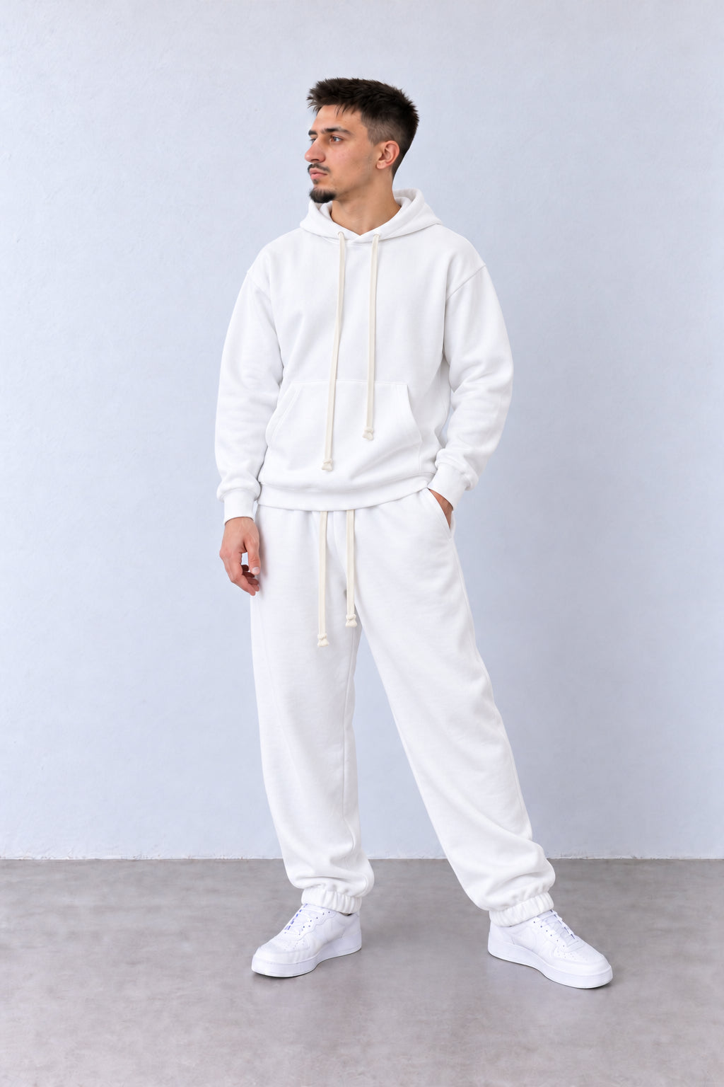 Бял мъжки анцуг с качулка и джогър панталони. На модел с леко обърната глава.