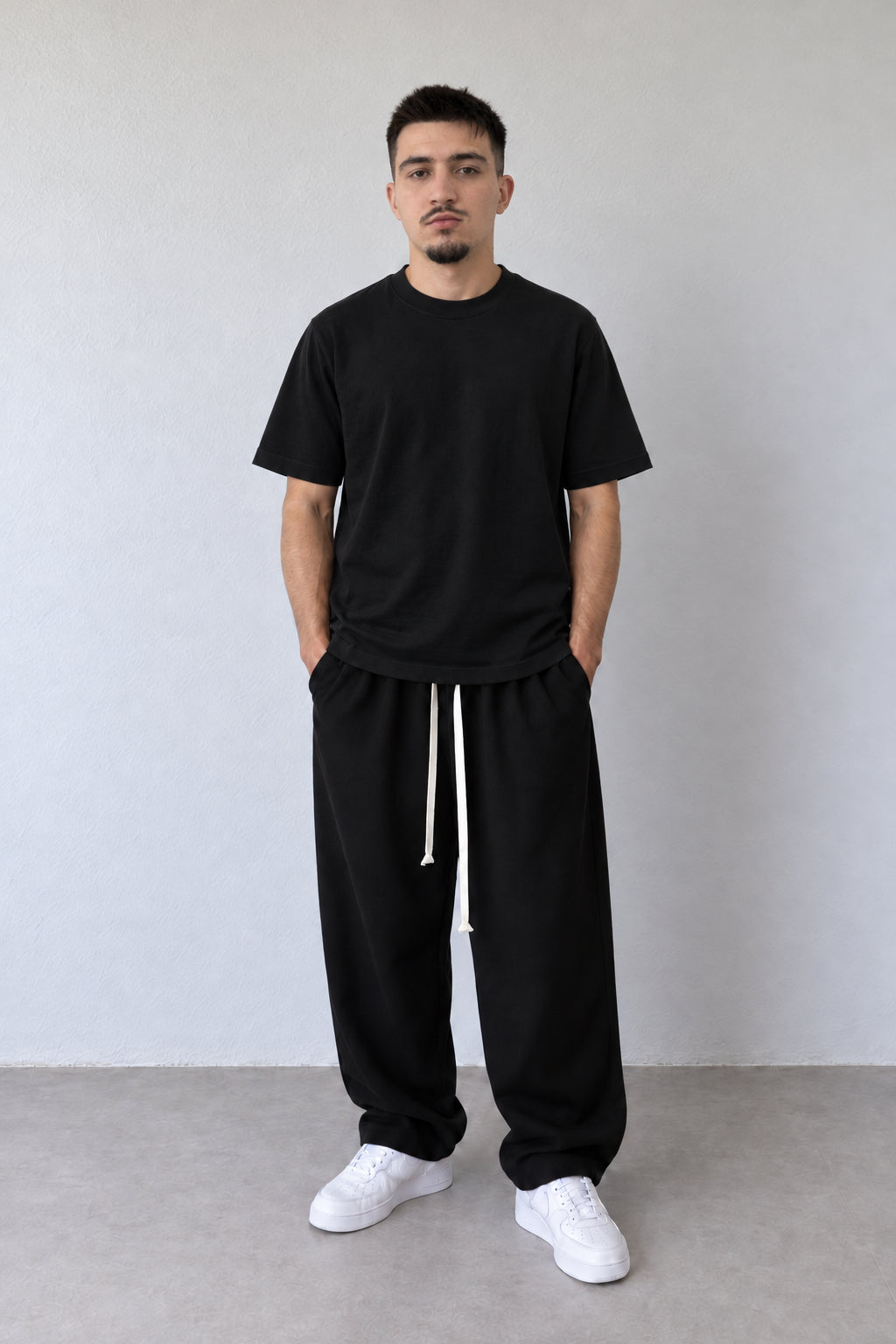 Tricou negru regular pentru bărbați DUCA-Q19 din bumbac, purtat cu pantaloni negri cu șnur lung, vedere integrală.